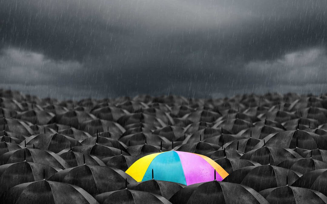 A colorful umbrella in an endless field of black umbrellas.