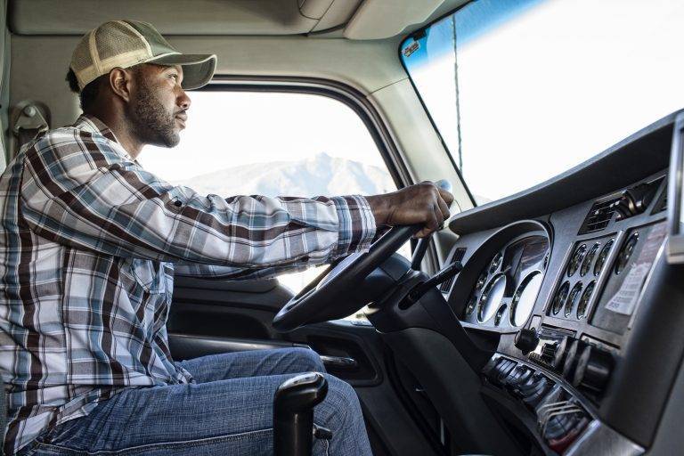 black man truck driver in the cab of his commercial truck